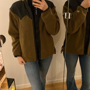 Hybrid Pile Fleece  - Helt ny mångsidig tröja i mjuk teddyfleece. Tvåvägsdragkedjan öppnar upp för ventilation i bägge ändar av dragkedjan, och den justerbara fållen stoppar kyliga vindar från att leta sig in under fleecen. 