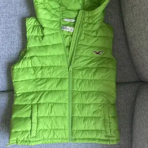 Perfect condition. The zipper functions well. Tight fit around the upper-body. Large hood. Bright green colour. Adjustable straps at the bottom (as seen in the 3rd picture). 