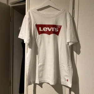 Vit Levi’s t-shirt - En helt basic vit levis t-shirt med själva trycket fram på bröstet. Storleken är lite knepig så hör av dig om du är intresserad och vill se fler bilder med tröjan på.