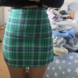 Monki rutig kjol i grön - Rutig pennkjol i grönt från Monki, i storlek 32. Använd en gång. Stretchigt tyg som passar XXS/XS/S. 