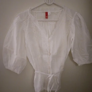 Romantisk luftig vit blus med vida ärmar och broderier. Strlk: 34 / XS-SMALL. Vintage look. Felfri. - Romantisk luftig vit blus med vida ärmar och broderier. Knytband i midjan. Strlk: 34 / XS-SMALL. Vintage look. Felfri.  Bild 3 är modell med likadan blus på.