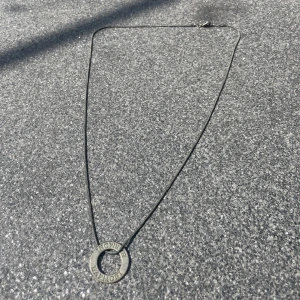 Silvrigt halsband  - Silvrigt halsband med en ring som berlock. Är i fint skick, behövs endast en liten putsning