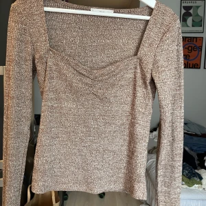 Långärmad brun topp - Långärmad brun topp med fyrkantig halsringning. Väldigt söt och kan användas både till fest och till vardags. Använd fåtal gånger och är i bra skick. 