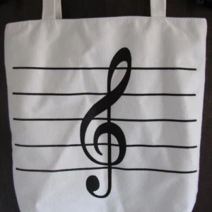 Ny vit handväska svart G-klav (piano-not) - Ny tyg väska, vit med svart g-klav. Snygg annorlunda! Liten ficka med dragkedja på insidan. (Ny oanvänd men vill nämna att zippern på dragkedjan inuti är lite böjd från tillverkningen, syns ju bara om man kollar noga och påverkar inte dragfunktionen.)