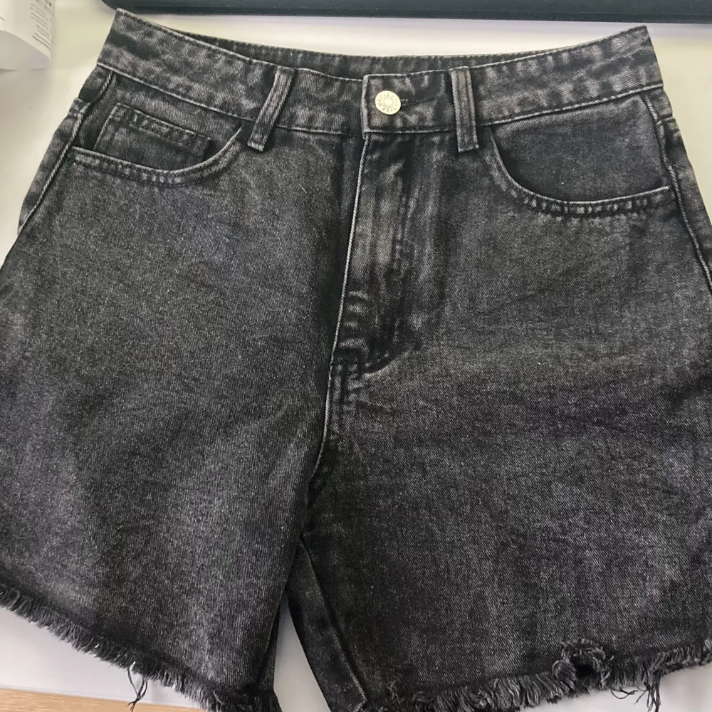 Svarta oanvända jeansshorts med äkta fickor. Färgen stämmer bäst överens i första bilden. 85% bomull 15% polyester. Säljs då de är för små för mig. Mått mätt platt: midja 36cm, längd 39cm och innerbenslängd 13cm.. Shorts.