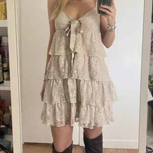 Klänning - Jättesöt klänning från Gina tricot. Ljus beige/puderrosa färg med champagne färgade band som man kan knyta hur man vill. Sitter som strl M