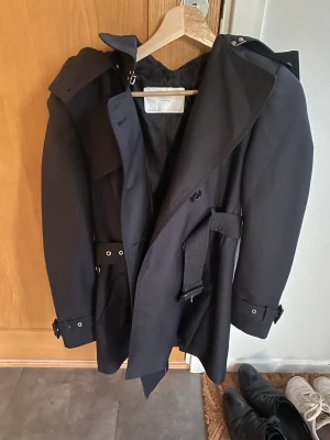 Zara, svart trenchcoat med huva - Zara, svart trenchcoat med huva och bälte i midjan, aldrig använd, som ny! Storlek: S, Material: Polyester
