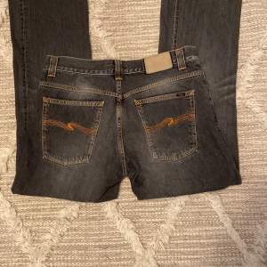 Säljer ett par lågmidjade bootcut Nudie jeans i färgen ”used black” med coola bakfickor i väldigt bra skick med inga defekter💗