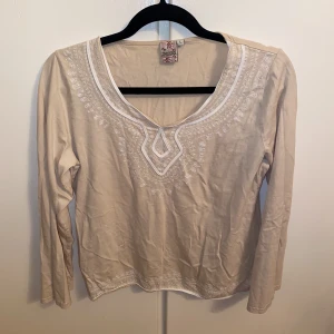 Långärmad tröja  - En beige långärmad tröja med broderade detaljer. Tröjan är från Indiska i storlek L.