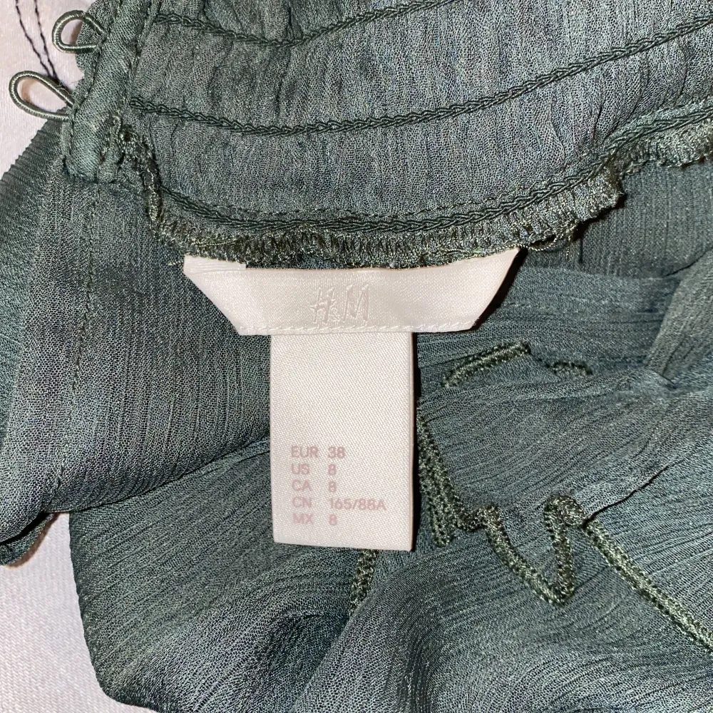 En gullig grön blus från H&M med urringning fram, vida armar och volanger! Säljer då den inte kommer till användning🤍. Blusar.