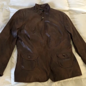 Brun läderjacka 46 - Brun läderjacka från vintage märket Bexleys, sann storlek 46. I väldigt bra skick, inga tecken på användning. Byst: 60cm. Finns inga bilder på men Dma gärna vid andra frågor eller funderingar. Köparen står för frakt.