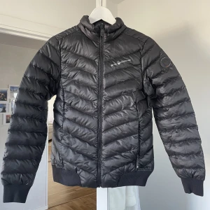 Dunjacka Sail Racing - Tidlös dunjacka utan luva från Sail Racing🍂 Nyskick då den är helt oanvänd dock utan lapp. Lite boxig i modellen🌟