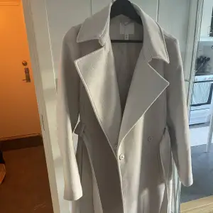 Lång kappa i färgen beige från H&M. Använd fåtal gånger.  Perfekt till hösten då den är lite tjockare. 