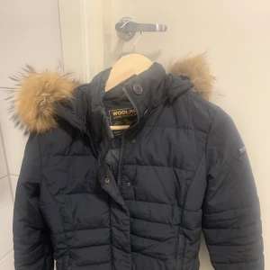 Vinter jacka  - En marinblå jacka från woolrich med tvättbjörns päls, säljes pga den ej får någon användning! Pris kan förhandlas vid snabb affär. 