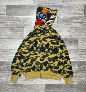 Bape hoodie yellow  -  bape hoodie i unika färgen yellow, använd två gånger tvättad en gång i handtvätt så varsamt använd. Inköpt för 4600. Väldigt rare färgkombo och väldigt populär och fet hoodie. Tags och påse medföljer