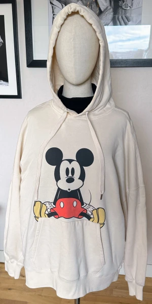Mickey Mouse Hoodie  - Jättefin offwhite färgad Mickey Mouse Hoodie i samarbete med Disney och H&M Lite mer oversized längre modell Mjukt ruggad insida. Jättefint skick! Använd 2ggr L73/bredd under ärm 65x2cm
