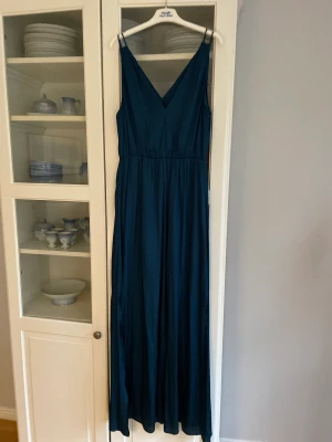 Petroleumfärgad klänning  - V-ringad klänning i 100% polyester. Använd en gång. 