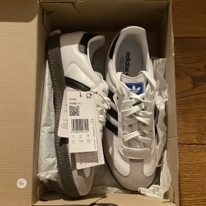 Adidas samba og svarta  - Helt nya Adidas Samba og skor (aldrig använda) i storlek 38. I cloud white med svarta ränder. Inköpta för 2100kr Pris 1150kr