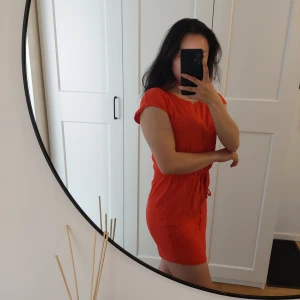 Röd klänning  - Klänningen går ned lite baktill och knyts vid midjan.  Den ser lite orange ut på bilderna men är röd.