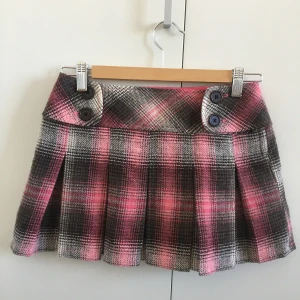 Rutig kjol - Min syrras gamla rutiga kjol, knappt använd och i jättefint skick! Har ett rosa tyg under, knäpps med en dragkedja i sidan. Längd: 31,5 cm. Midja: 33,5 cm. Skriv för fler bilder!