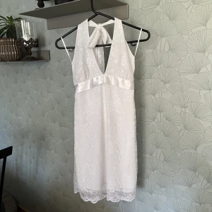Vit sommar/studentklänning - Drömmig halterneckklänning i spets, perfekt till studenten, skolavslutning eller sommaren. Köpt second hand, men ursprungligen från Gina Tricot. Stl 36, men passar nog 34/38 också eftersom den kan justeras i nacken och med bandet i midjan som knyts bak :)