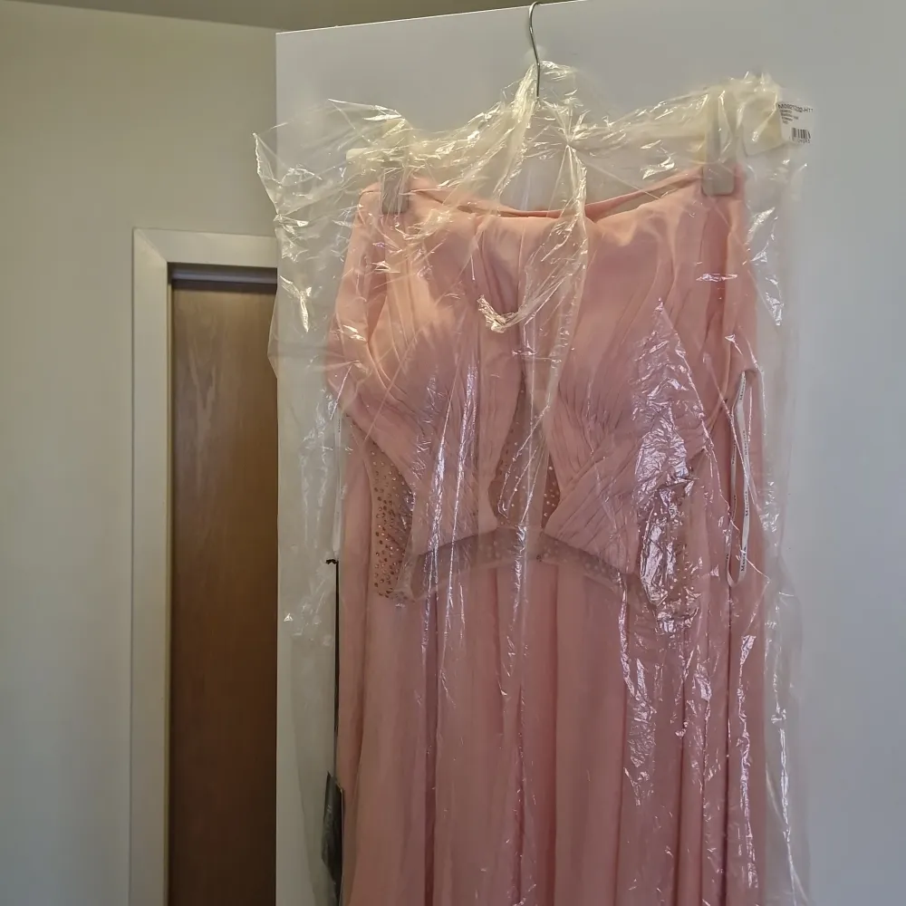 Klänning oöppnad fortfarande ettikett och plasten kvar, persiko färgad, möjligtvis balklänning eller cocktail klänning . Kjolar.
