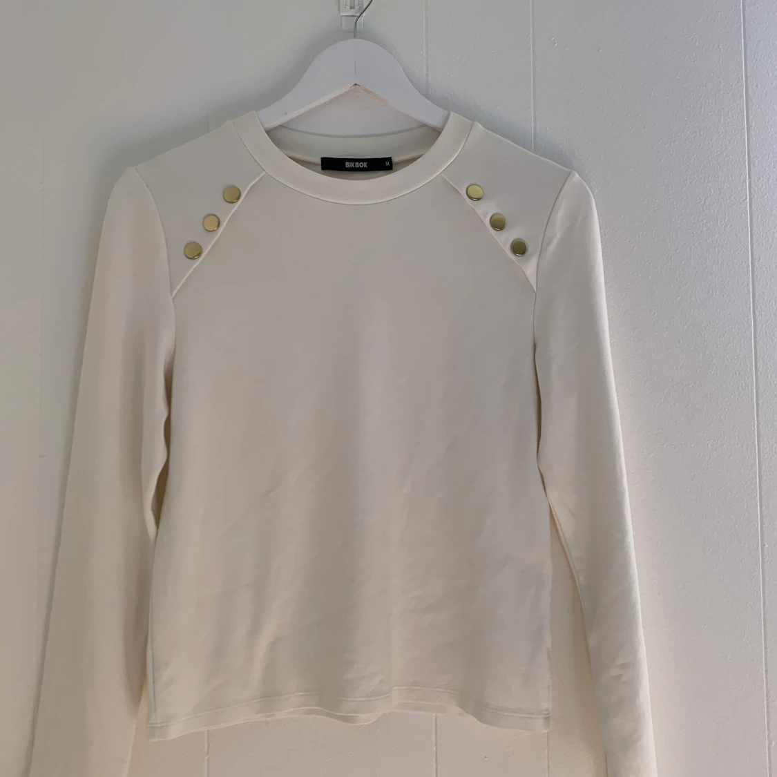 Vit tröja med guldknappar