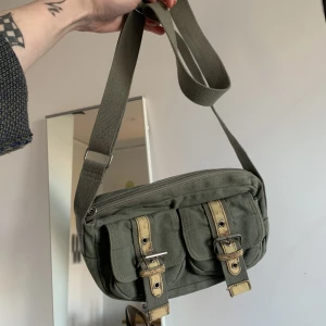 Militärgrön väska  - Liten grön väska, kan ha kort eller långt band perfekt för utekvällar, många fickor 