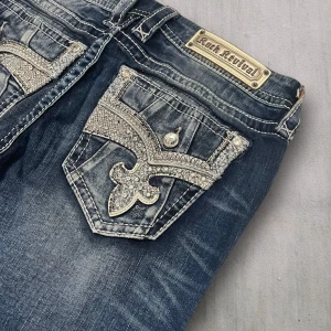 R05 Rock Revival Bootcut jeans  - Rock Revival jeans i model Boot 💜 Tag 29W 💜Midja (rakt över) 37cm 💜 Innerben 76cm 💜 Ytterben 97cm 💜 Benöppning 22cm 💜  💜Våra mått blir W=29, L=29 💜 Men jämför alltid måtten💜R05