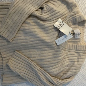 Stickad Zara tröja  - En jättefin oanvänd beige stickad tröja från Zara. Prislappen är kvar. Original pris:265kr. Passar säkert nån storlek större💗💗