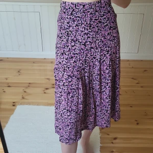 Lilablommig kjol - Sommrig kjol som är medel lång. Storlek S, 64 cm i midjan och 78 cm lång. Dragkedja i midjan. Jag är 173 cm lång. 