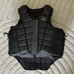 Ridväst  - En säkerhetsväst för ridning. Märket Jacson köpt på hööks. Västen är några år gammal. Med dragkedja och kardborreband. Risternas i axlar och midja. Jag är 175 och har haft västen inspänd på minsta. Går att göra större i omkrets.  