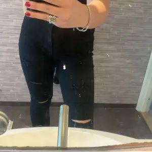 Svarta jeans med hål och slitningar 