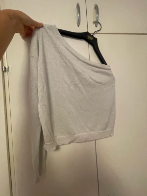 Festtopp - Snygg silver glittrig stickad one-shoulder fest topp! Från NA-KD. Älskar denna men slutat använda på senaste så säljer!