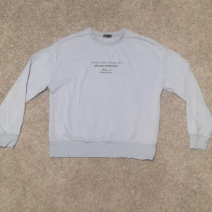 Collegetröja blå - Superfin och härlig collegetröja med tryck som är i nyskick. I en babyblå färg. Är i storlek M men är liten i storleken. 