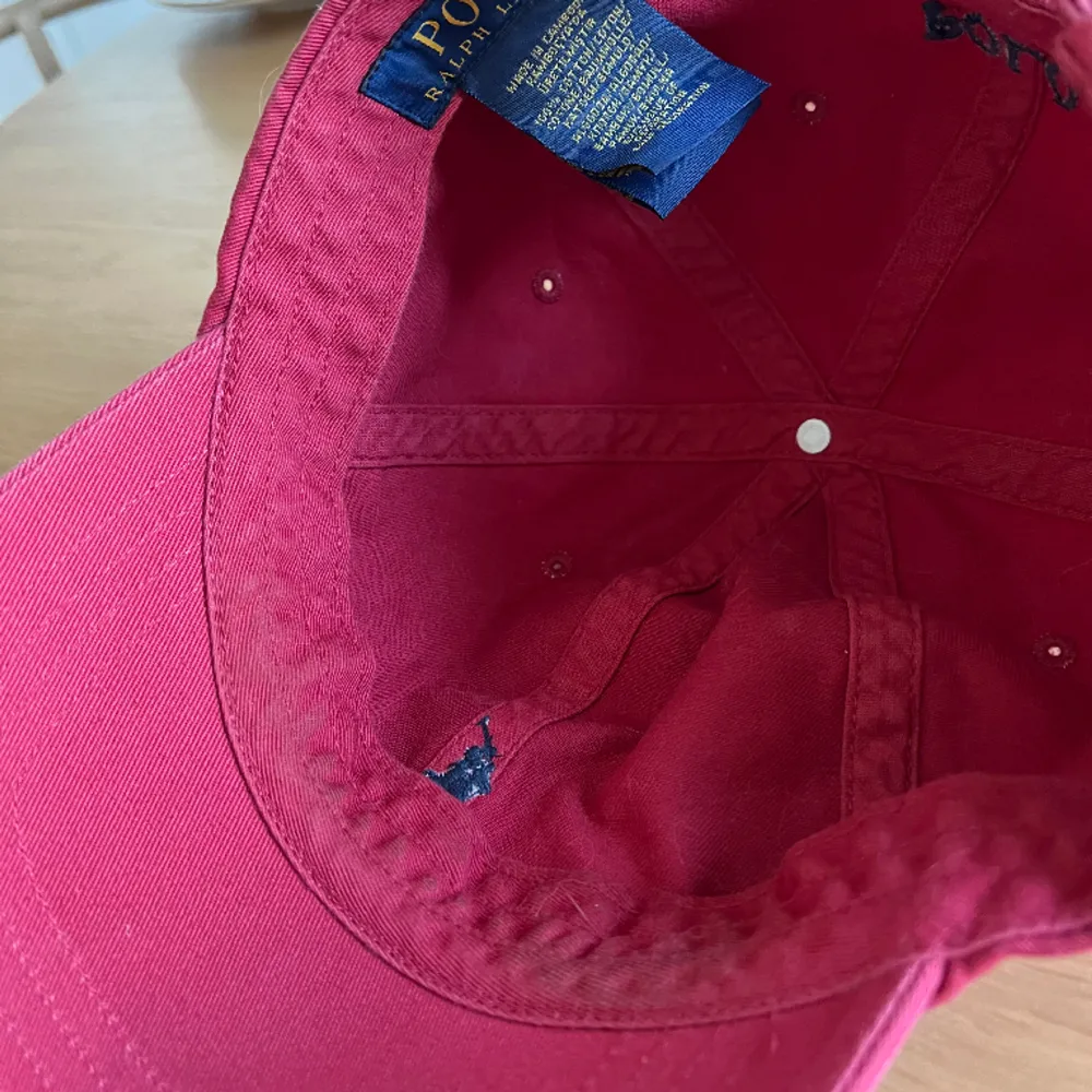 Röd keps från Ralph Lauren, den är solblekt samt lite smutsig på insidan som ni ser på bilden, har inte testat tagit bort men går säkert att tvätta bort. . Accessoarer.