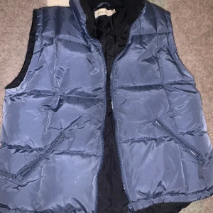 Blå Puffväst - Säljer en jättefin blå väst då den ej används, är i mycket bra skick. Jackan är i storlek XL/EUR 5 men passar bra på mig som bär storlek S. Defekt: Har några små vita prickar på framsidan av västen. 