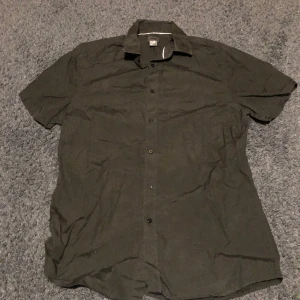 Skjorta - Svart kortärmad skjorta, knappt använd, har en liten röd fläck på kragen men går bort lätt om man pillar med nageln;)