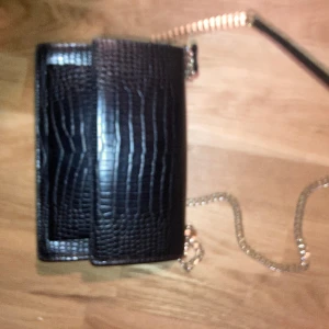Svart skin väska (handväska) - De är en svart skin väska lång kedja guld har ba ta andvändt två gånger så köp gärna 😁