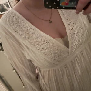 Vit blus med spets och broderi - Vit blus/top med spets på, finns 2 band på sidan som kan knytas fram eller bak. Bara testad. Skriv för fler bilder 