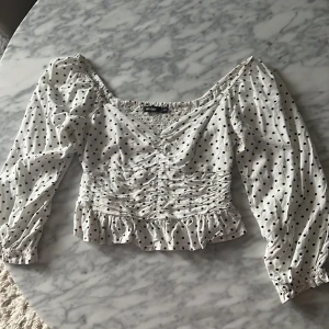 Prickig topp - Prickig topp med volang ner till och 3/4 ärm, smock på ryggen 