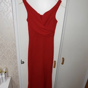 Lång röd klänning  - Säljer denna fina offshoulder långklänning.  Storlek XS , den är lite längre bak och har även en slits som man kan se på bilden.  Använd bara en gång!  Materialet är super skönt så den är bekväm att ha på sig.  Köptes för 1200:-