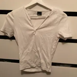 Söt tight vit T-shirt med knappar mot toppen, inga tecken på användning då den bara använts en gång.