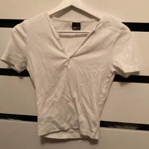 Tröja med knappar  - Söt tight vit T-shirt med knappar mot toppen, inga tecken på användning då den bara använts en gång.