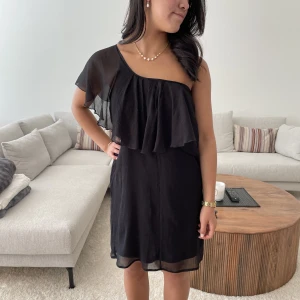 Svart one shoulder klänning - En sjukt snygg svart klänning med volang, med två ärmar med går också att styla som one shoulder🥰🥰 kolla jättegärna mina andra annonser!!