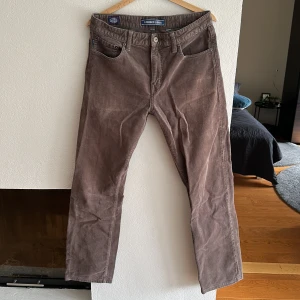 Manchester Byxor Superdry  - Straight fit Superdry Manchester. Färgen är grå men kan dra sig åt det brunare hållet i visst ljus.