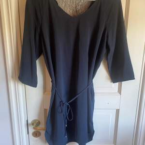 Mörkblå klänning med spets vid ryggen, band runt midjan och trekvartsärm. Klänningen är knappt använd. Inköpt på Vila i storlek M.
