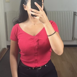Hallonröd topp - Jättefin hallonröd v-ringad topp som framhäver nyckelbenen. Knapparna går inte att öppna.   Är i storlek XS men passar även S. 