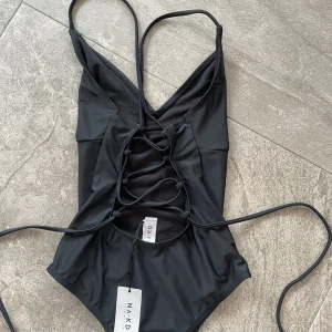 Svart Baddräkt  - En oanvänd baddräkt från NA-KD. Lapparna är kvar. Säljer pga fel storlek. Snörning i ryggen