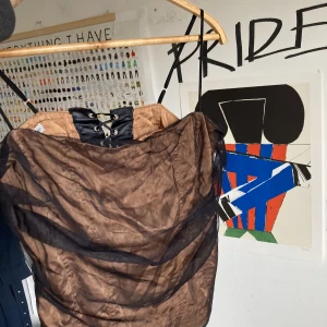 Korsetttopp - 2000-tals topp, ett underlaget av ljusbrun polyester och ett ytterligare lager av svart tyll. Den har en korsettdetalj på ryggen, det är relativt slitet då jag också köpte det secondhand men det går definitivt att använda. 